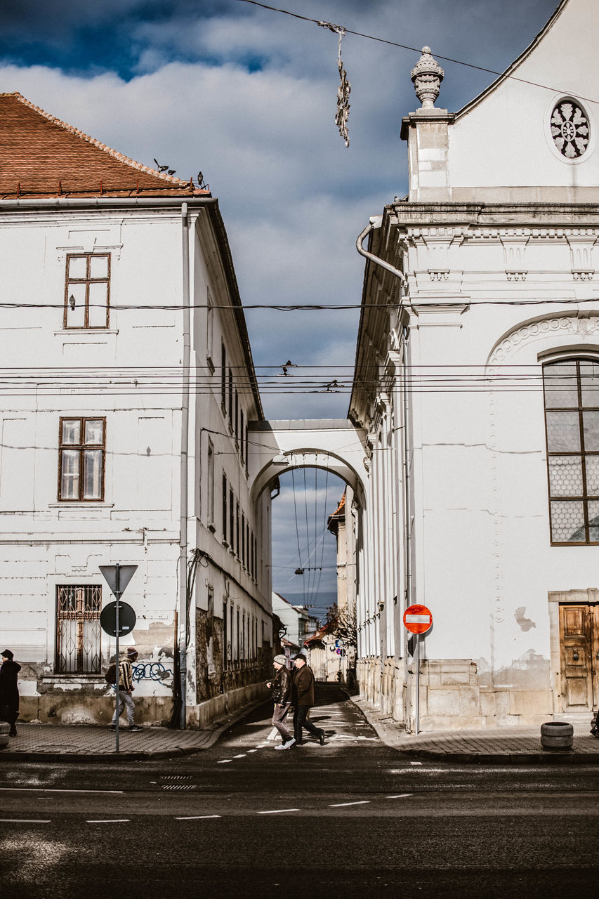 architecture, building exterior, built structure, transportation, street, city, building, sky, cloud - sky, animal themes, mode of transportation, real people, nature, day, animal, domestic animals, horse, road, mammal, domestic, outdoors