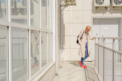 Young woman with backpack standing by railing in corridor