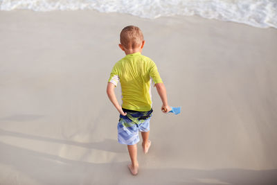 Rear view of boy walking at beach