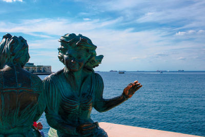 Statue by sea against sky