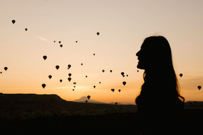 Silhouette woman standing against sky during sunset