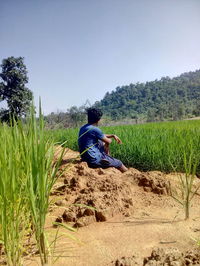 Rear view of man sitting on land