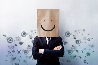 Digital composite image of businessman wearing paper bag with anthropomorphic face 