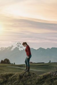 Full length of woman standing on field against mountain