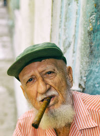 Portrait of senior man wearing cap smoking cigar