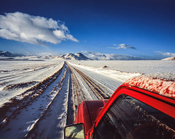 Snow covered road by land against sky