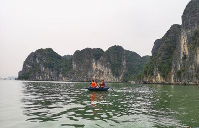 People on canoe by sea against clear sky