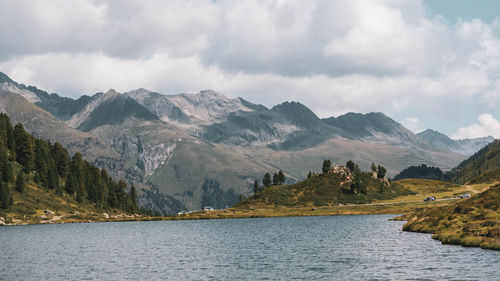 Scenic view of mountains and lake against cloudy sky