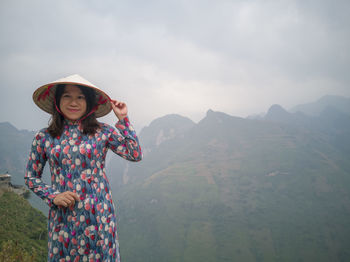 Woman standing by mountains against sky