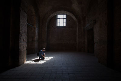 Sunlight falling from window on man kneeling in old building