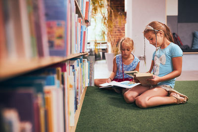 Schoolgirls looking for books in school library. elementary education. back to school