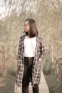 Portrait of young woman standing against trees