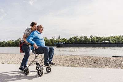 Woman pushing her old father sitting on wheeled walker