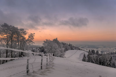 Scenic view of snow covered field against sky during sunset