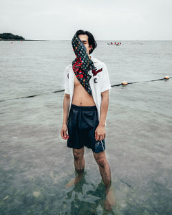 Rear view of man standing in sea against sky