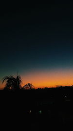 Silhouette trees on field against clear sky at sunset