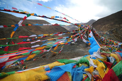 Multi colored flags hanging on mountain against sky