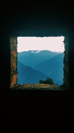 Scenic view of mountains against sky seen through window