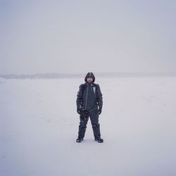 Portrait of man standing on snow covered field during winter