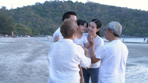 Rear view of people standing on beach