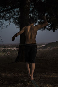 Rear view of shirtless man standing on field