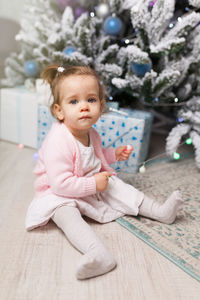 Cute girl sitting on floor at home during christmas