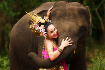 Female in traditional clothing embracing elephants