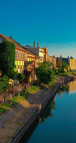 Canal by buildings against blue sky