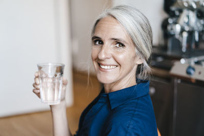 Portrait of smiling businesswoman holding glass of water