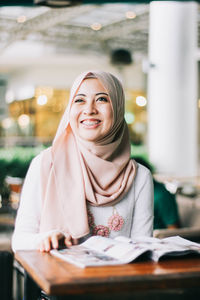 Portrait of a smiling young woman sitting at restaurant