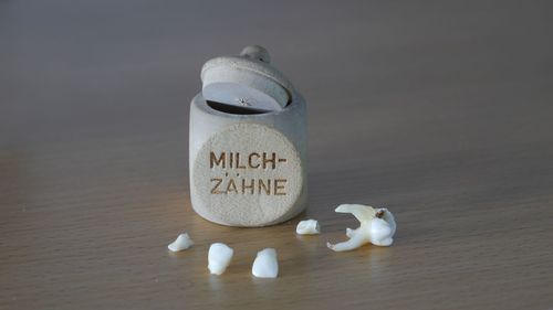 Close-up of broken tooth and container on table