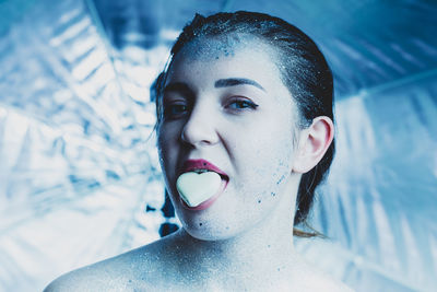 Portrait of young woman with glitters eating candy