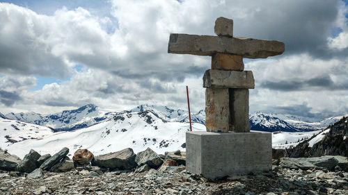 Cross on snow covered mountains against sky