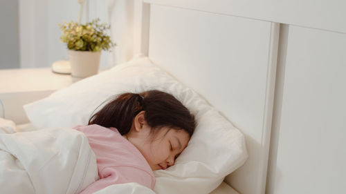 Portrait of young woman sleeping on bed at home