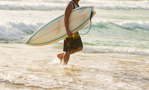 Rear view of man with surfboard on beach