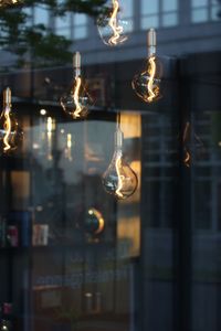 Close-up of illuminated light bulbs hanging from glass window