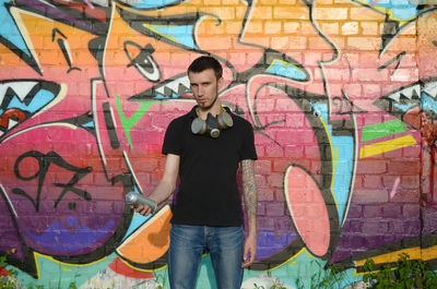 Full length of young man standing against graffiti wall