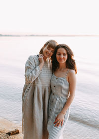 Two relaxing happy smiling girls in summer sundresses by the sea