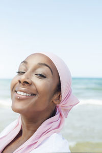 Portrait of smiling woman at beach against clear sky