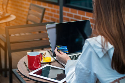 Midsection of woman using laptop while sitting at table in cafe