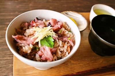 High angle view of rice and meat in bowl on wooden table