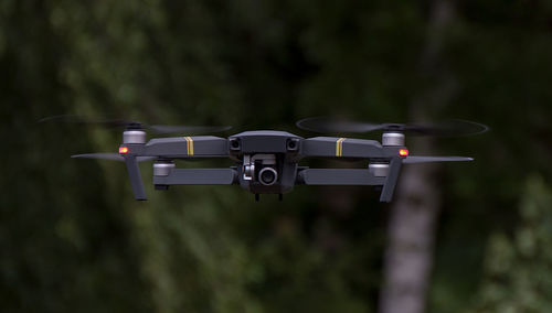 Close-up of drone flying against trees