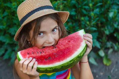 Portrait of smiling girl wearing hat eating watermelon