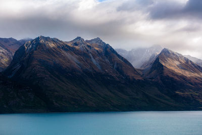 Scenic view of mountains and lake against cloudy sky