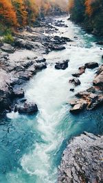 High angle view of stream flowing through rocks during autumn