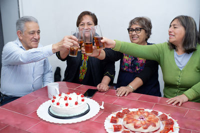 An older man with his friends celebrating and toasting a birthday at an indoor party. old birthday
