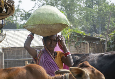 Portrait of woman holding fodder bag on her head