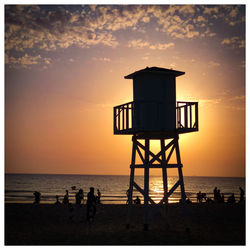 Silhouette hut on beach against sky during sunset