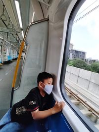 Full length of boy sitting on train window