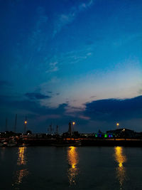 Illuminated bridge over river against sky at night